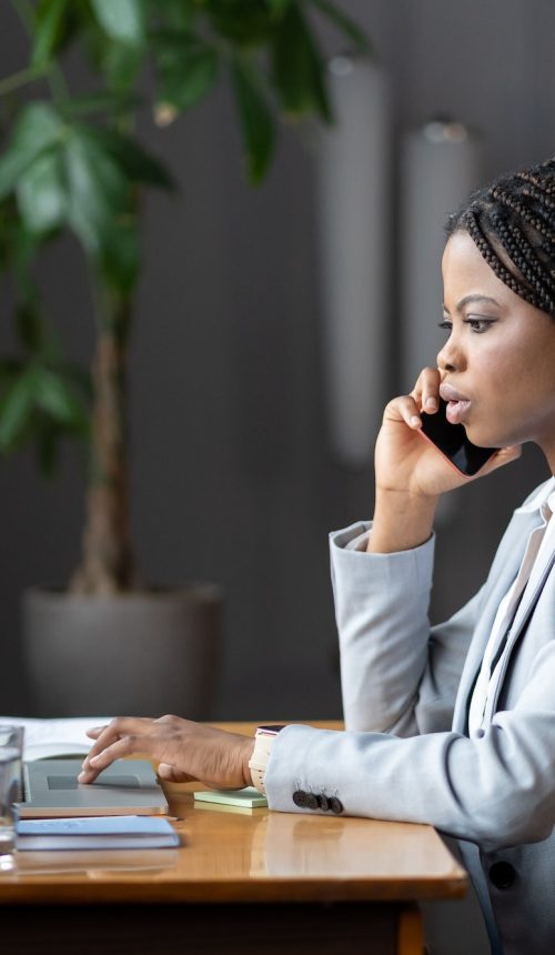 afro-female-business-consultant-interacting-with-client-over-phone-and-entering-data-on-laptop.jpg